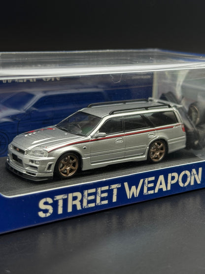 Nissan Stagea R34 Argent / Bande Rouge – Street Weapon 1/64 | 107/499 SVRdiecast