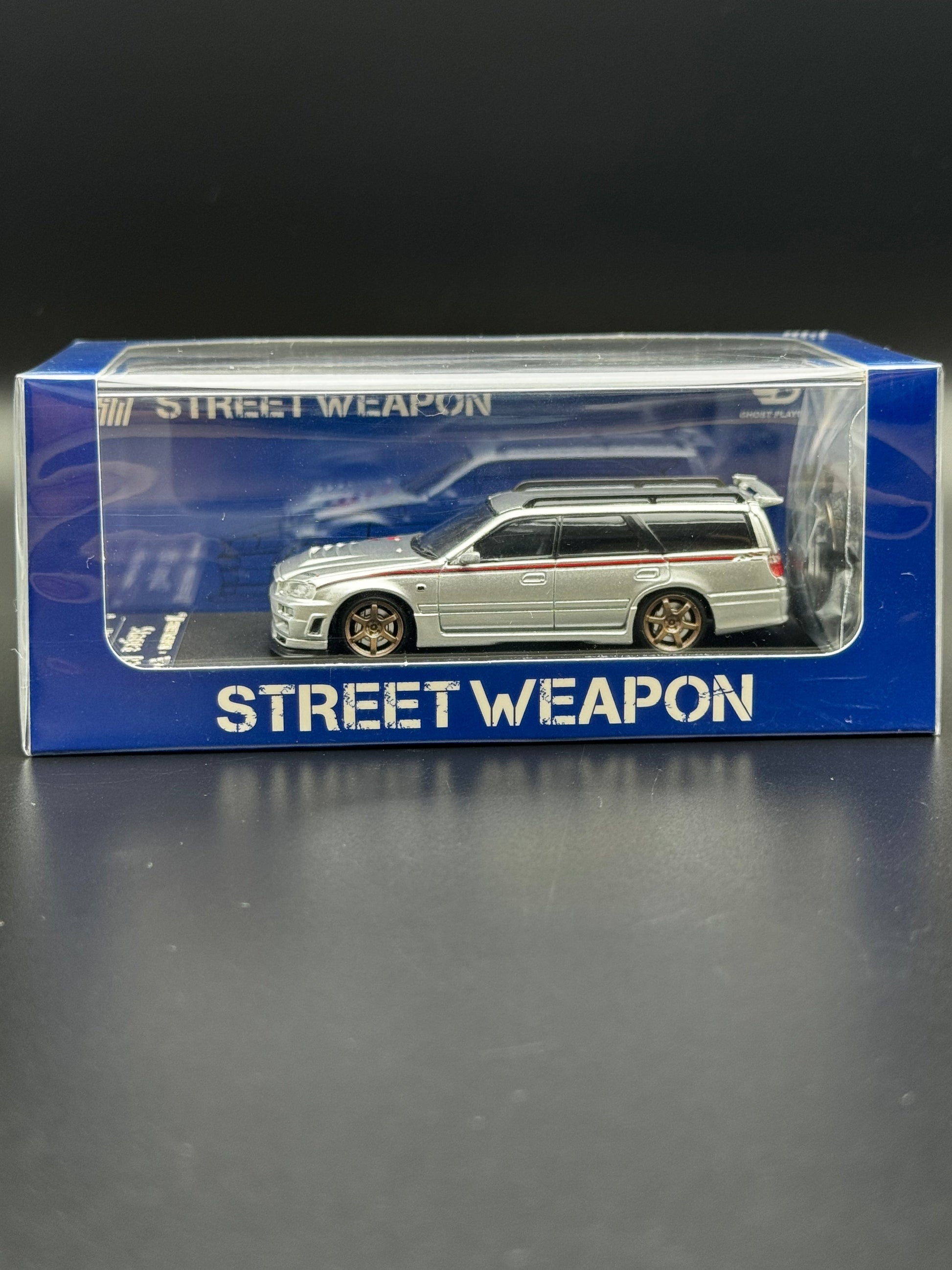 Nissan Stagea R34 Argent / Bande Rouge – Street Weapon 1/64 | 107/499 SVRdiecast